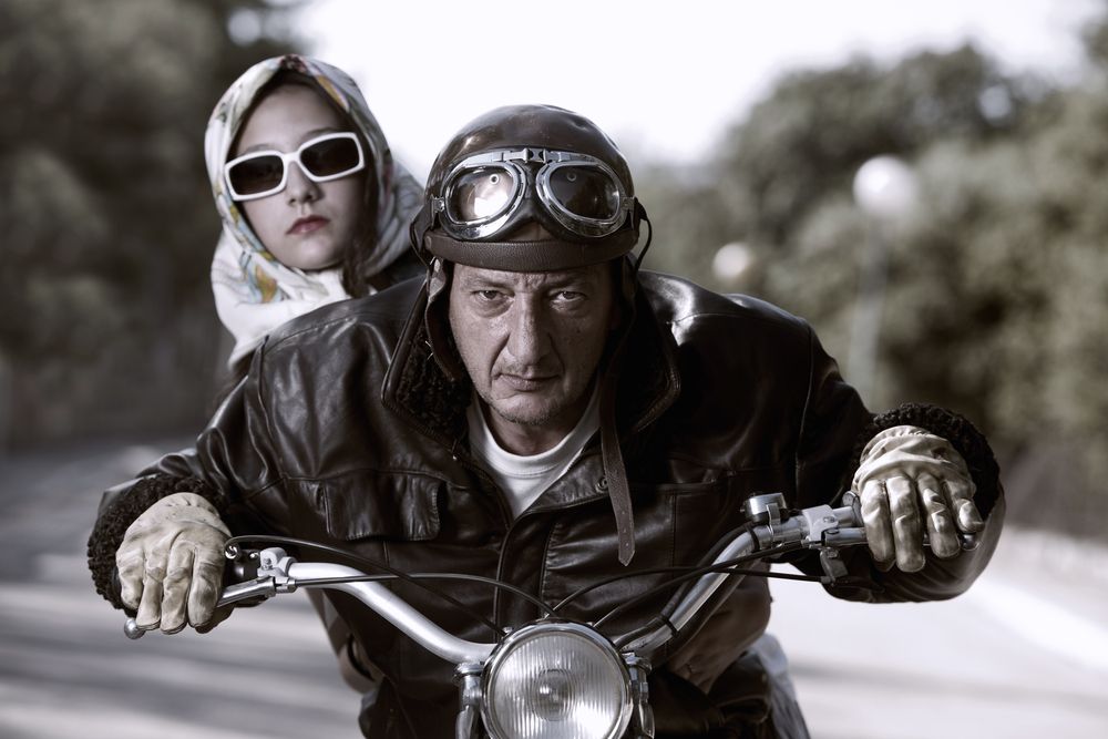 a man and a women wear a safety glasses while riding a motorbike
